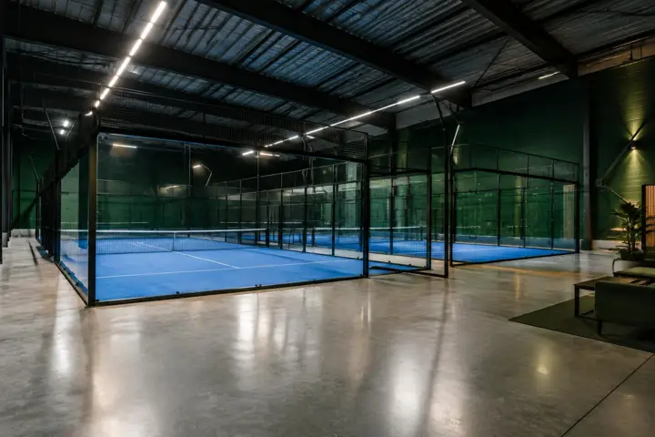 Modern indoor padel hall with linear lighting and dark green walls